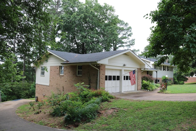 view of side of property featuring a garage, brick siding, concrete driveway, and a lawn