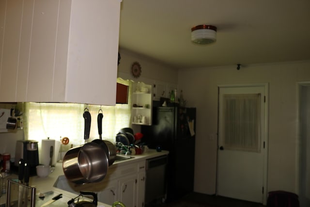 kitchen featuring stainless steel dishwasher, freestanding refrigerator, light countertops, and white cabinetry