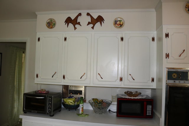 room details with wall oven, a toaster, light countertops, ornamental molding, and white cabinetry