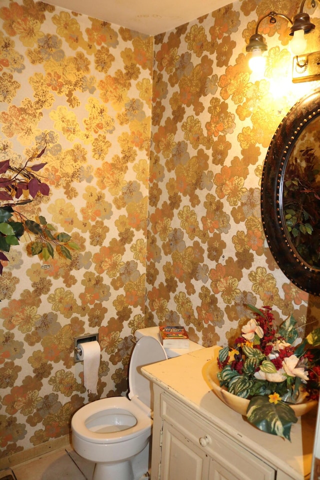 bathroom featuring vanity, toilet, and wallpapered walls