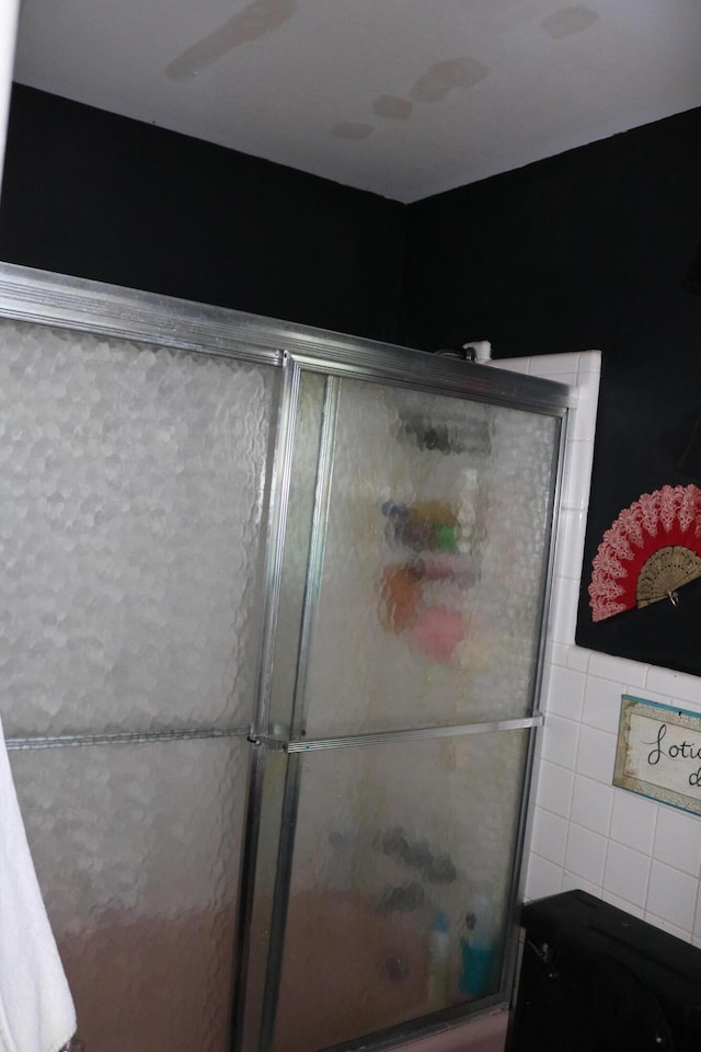 bathroom featuring a shower with door and tile walls