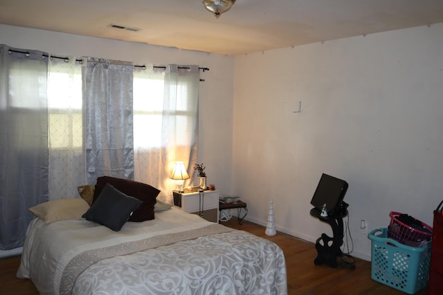 bedroom featuring visible vents, baseboards, and wood finished floors