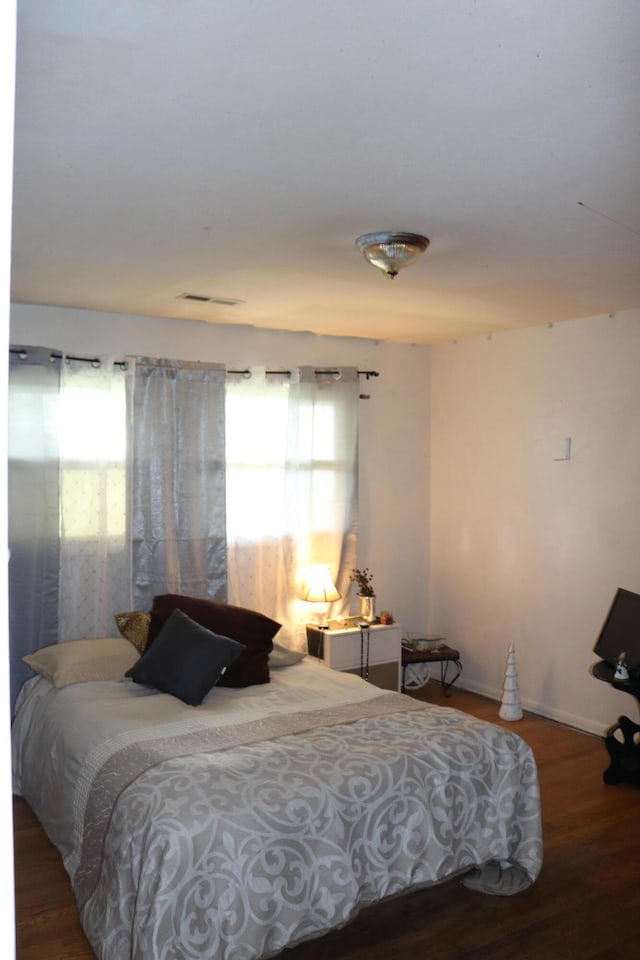 bedroom with visible vents, baseboards, and wood finished floors