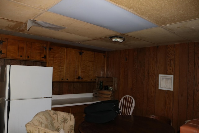 kitchen with wooden walls, brown cabinets, and freestanding refrigerator