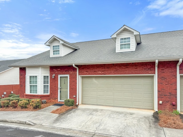 view of front of house featuring brick siding, an attached garage, driveway, and a shingled roof