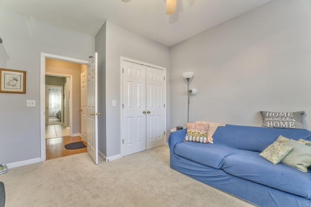 carpeted living area with ceiling fan and baseboards