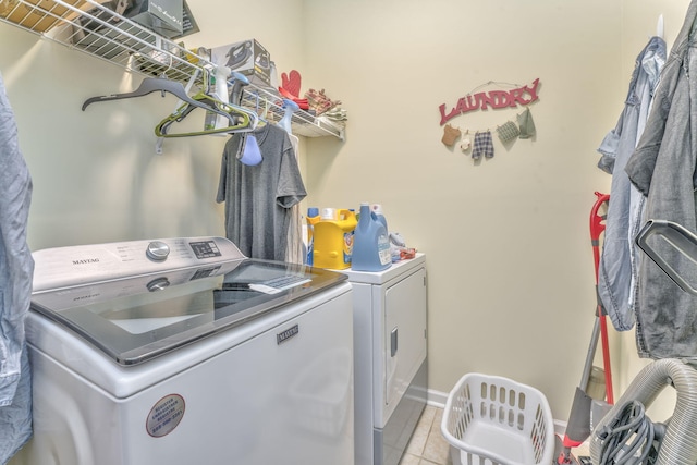 laundry area featuring washer and dryer, laundry area, light tile patterned floors, and baseboards