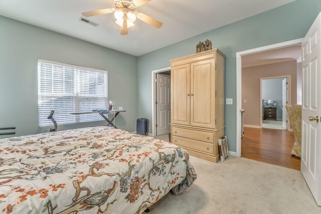 bedroom featuring a ceiling fan, light colored carpet, visible vents, and baseboards