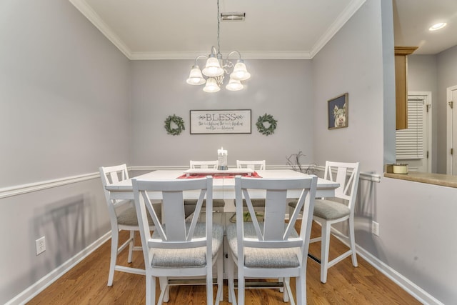 dining space featuring a notable chandelier, ornamental molding, baseboards, and wood finished floors