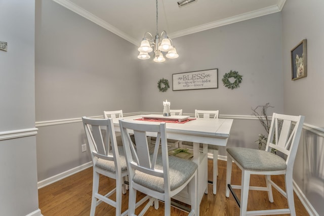 dining room featuring an inviting chandelier, crown molding, baseboards, and wood finished floors