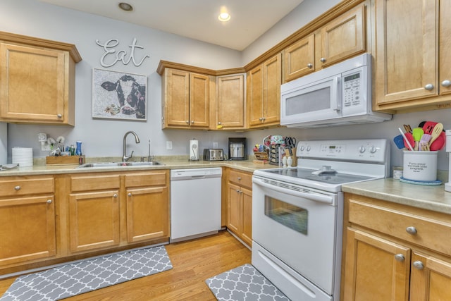 kitchen with a sink, recessed lighting, white appliances, light wood-style floors, and light countertops