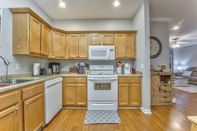 kitchen with a sink, white appliances, light wood-style floors, and light countertops