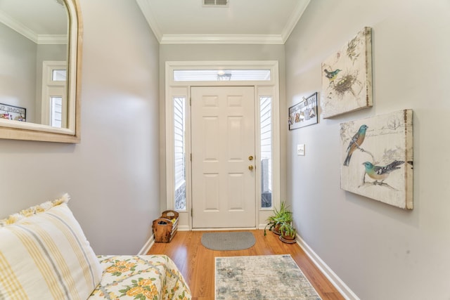 foyer with visible vents, wood finished floors, and crown molding