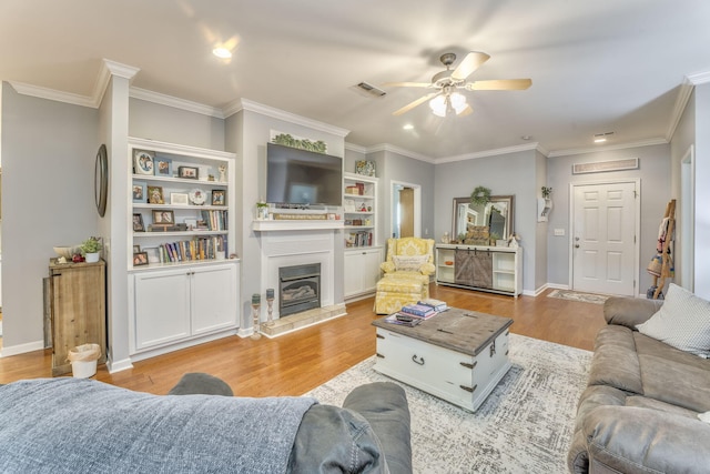 living area featuring visible vents, baseboards, light wood-style floors, and ornamental molding