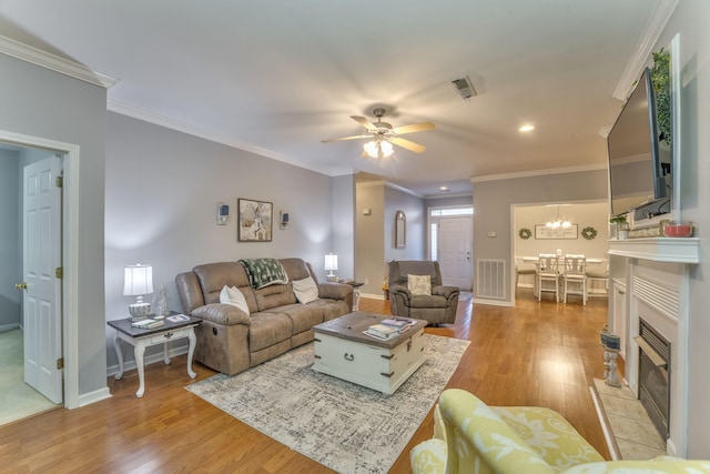 living area featuring light wood finished floors, visible vents, crown molding, and baseboards