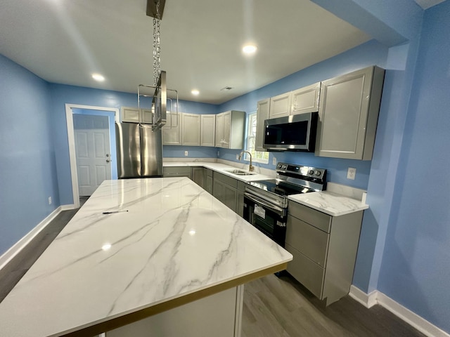 kitchen featuring a sink, a center island, appliances with stainless steel finishes, baseboards, and dark wood-style flooring