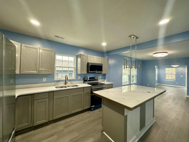 kitchen featuring a sink, stainless steel appliances, a kitchen island, and light wood finished floors