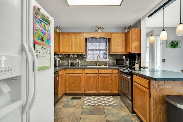 kitchen with a sink, decorative backsplash, dark countertops, and appliances with stainless steel finishes