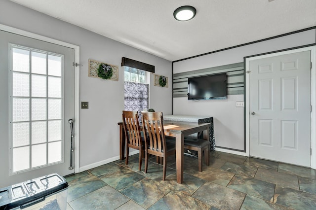 dining space with stone finish flooring and baseboards