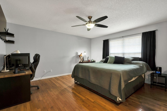 bedroom with ceiling fan, wood finished floors, baseboards, and a textured ceiling