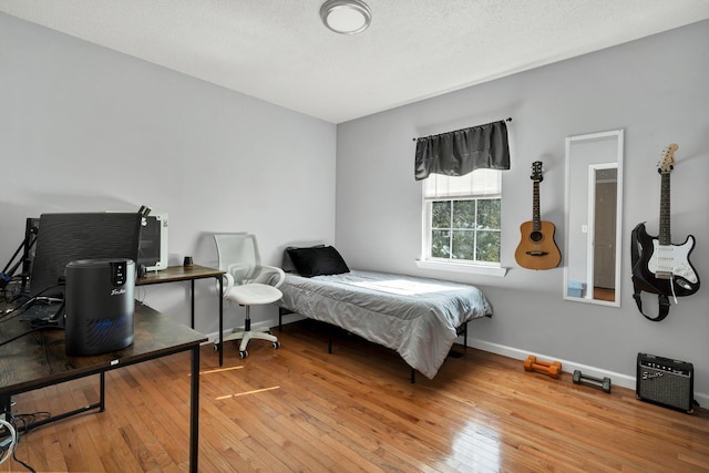 bedroom with baseboards, light wood-style floors, and a textured ceiling