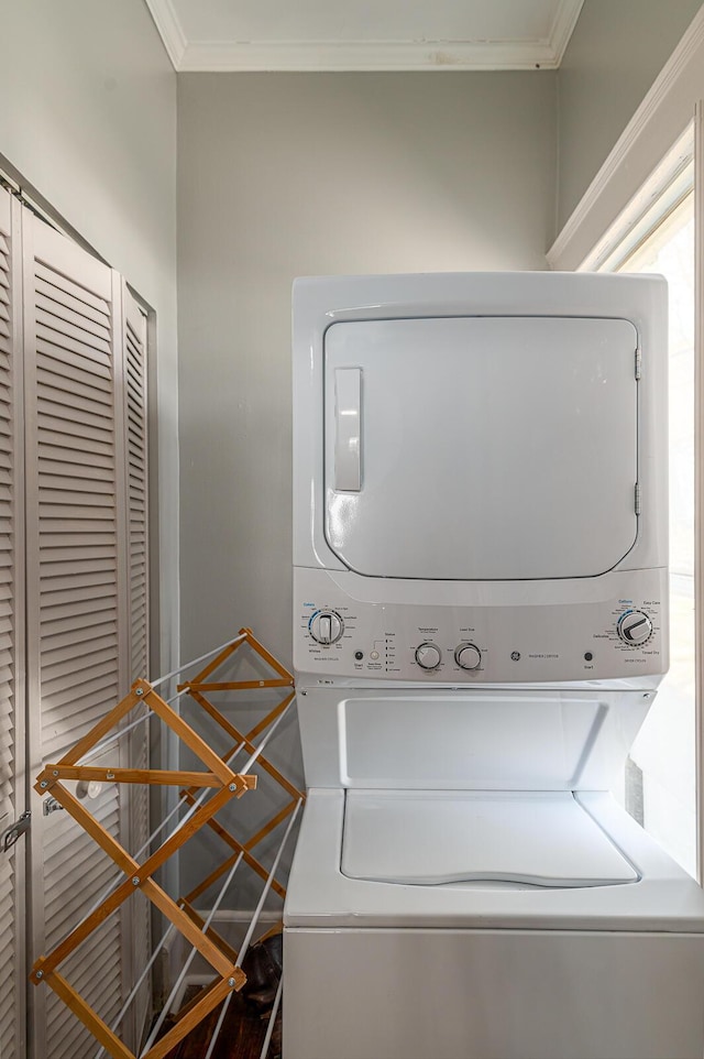 laundry room with crown molding, laundry area, and stacked washing maching and dryer