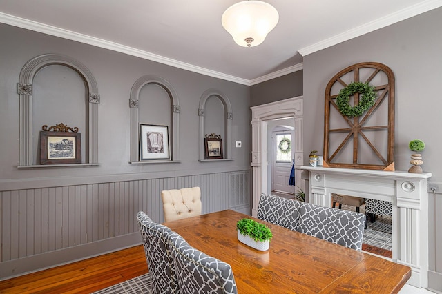 dining room featuring a wainscoted wall, wood finished floors, and ornamental molding