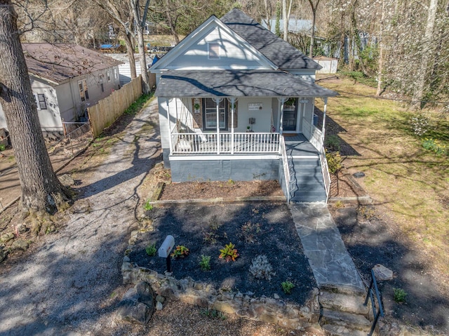 view of front of house with a porch, fence, and roof with shingles