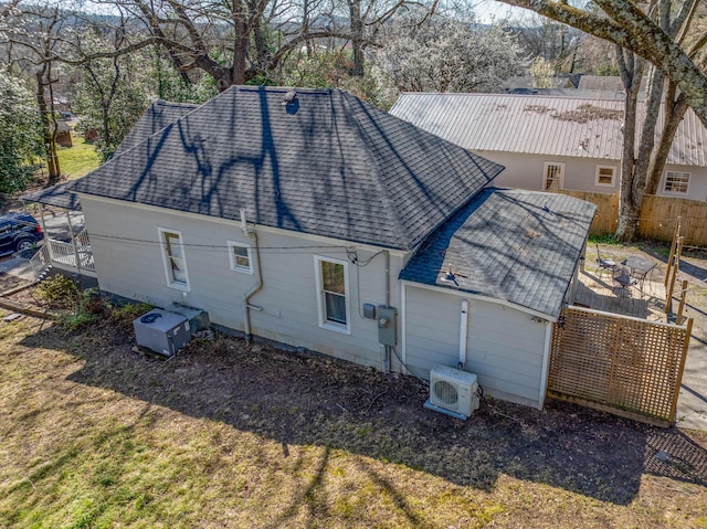 exterior space with fence, roof with shingles, ac unit, central AC unit, and a garage