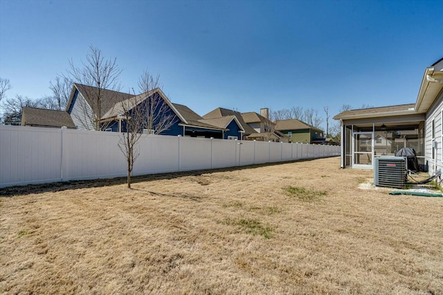 view of yard with a sunroom, central AC unit, and fence