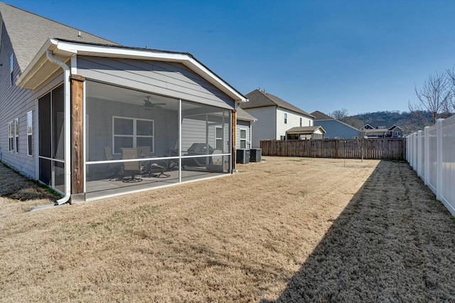 rear view of property featuring central AC, a fenced backyard, a lawn, and a sunroom