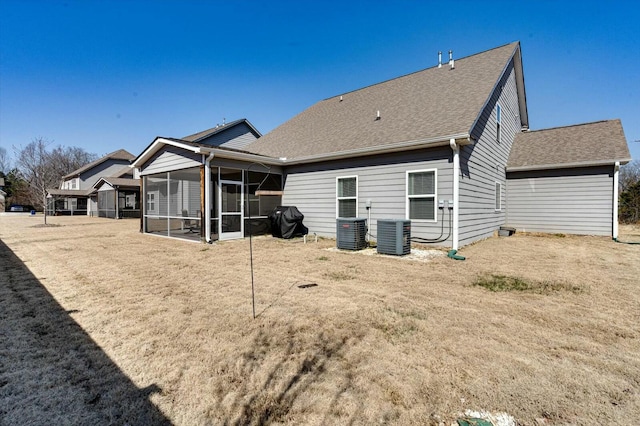 back of property featuring a yard, a shingled roof, central AC, and a sunroom