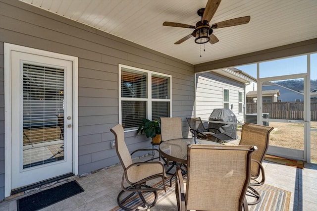 view of patio / terrace with outdoor dining space, glass enclosure, ceiling fan, and fence