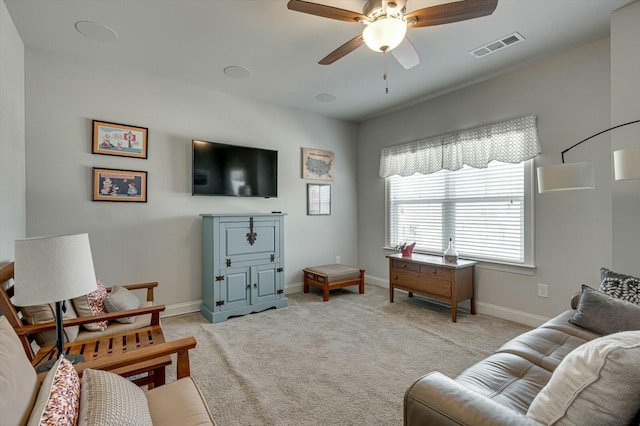 living room featuring visible vents, light carpet, baseboards, and a ceiling fan