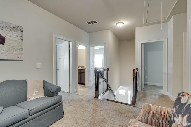 living area featuring light carpet, visible vents, attic access, and baseboards