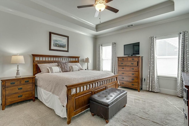 bedroom featuring a tray ceiling, crown molding, visible vents, and light carpet