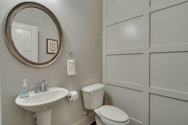 bathroom with a sink, baseboards, and toilet