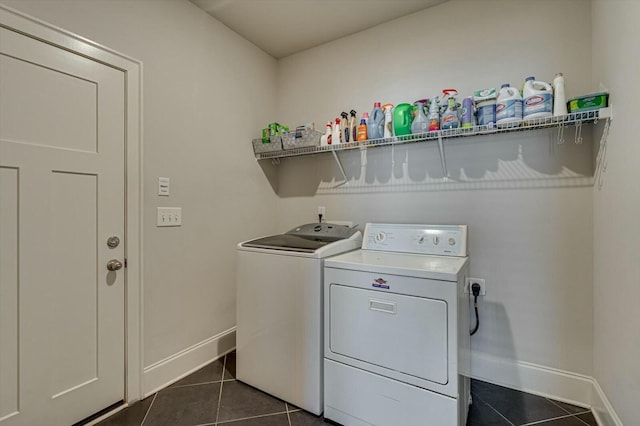 laundry area with baseboards, dark tile patterned floors, laundry area, and washer and clothes dryer