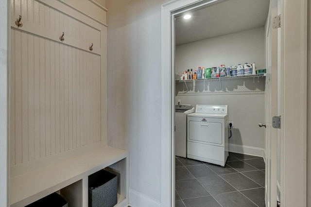 laundry room featuring washer and dryer, laundry area, dark tile patterned flooring, and baseboards