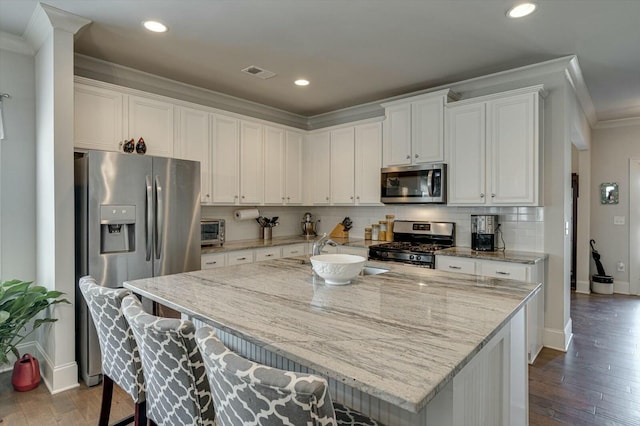 kitchen with visible vents, ornamental molding, white cabinets, appliances with stainless steel finishes, and tasteful backsplash