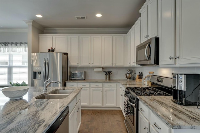 kitchen featuring a sink, stainless steel appliances, white cabinets, and crown molding