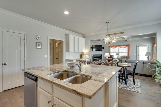 kitchen with dishwasher, crown molding, open floor plan, and a sink