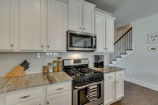 kitchen with baseboards, dark wood finished floors, stainless steel appliances, white cabinetry, and tasteful backsplash