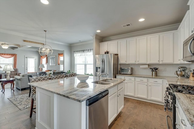 kitchen with visible vents, a sink, white cabinets, appliances with stainless steel finishes, and open floor plan