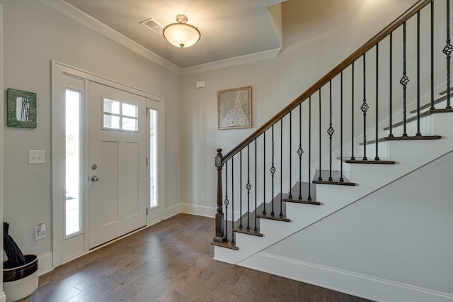 foyer entrance featuring wood finished floors, baseboards, visible vents, ornamental molding, and stairs