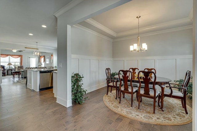 dining space with dark wood-style floors, a raised ceiling, crown molding, and an inviting chandelier