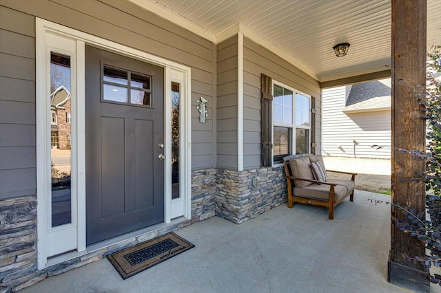 entrance to property featuring a porch and stone siding