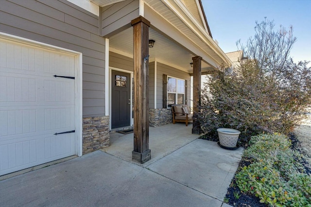 property entrance featuring stone siding, a porch, and a garage