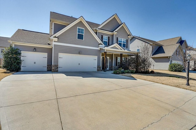 craftsman-style home with a garage, stone siding, and driveway