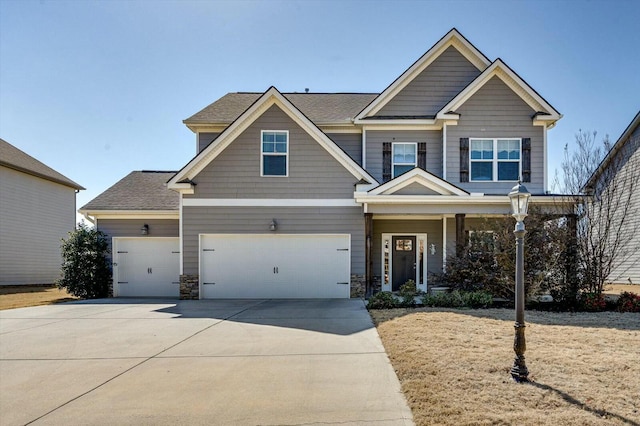 craftsman-style home with stone siding, an attached garage, roof with shingles, and driveway